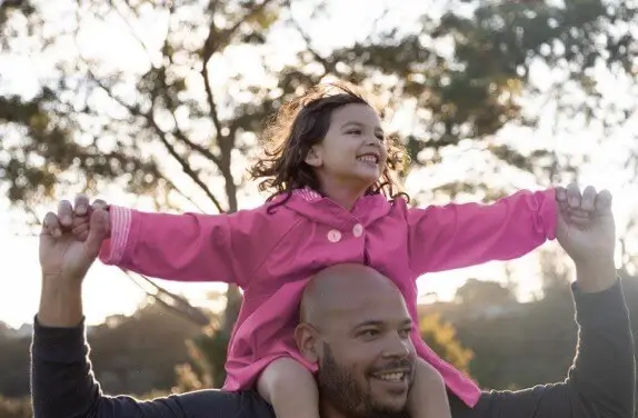 Daughter sitting on father's shoulders